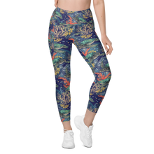 Load image into Gallery viewer, A model wearing high-waisted, ankle-length leggings with a vibrant coral reef pattern on a dark blue background, paired with white sneakers against a plain white studio background.